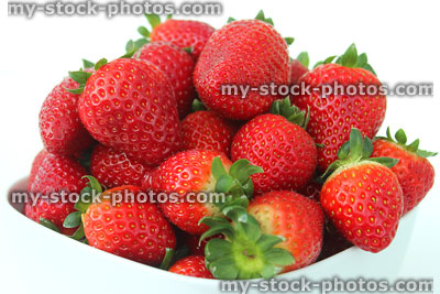Stock image of fresh red strawberries, strawberry fruit / stems, white dish
