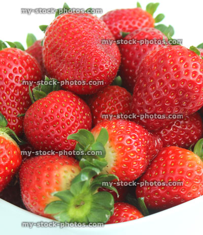 Stock image of fresh red strawberries, strawberry fruit / stalks, white dish