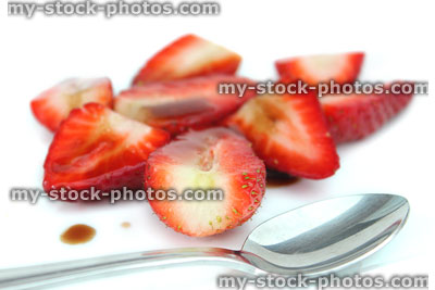 Stock image of sliced strawberries with balsamic vinegar, sugar, spoon, healthy dessert