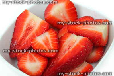 Stock image of red strawberry halves in dish, sliced in half
