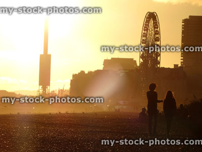 Stock image of children walking on Brighton beach at sunset, big wheel