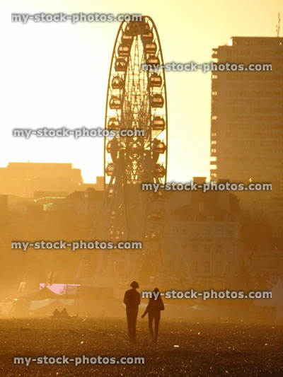 Stock image of boy and girl walking on sunset beach, big wheel