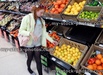 Stock image of teenage girl at supermarket, shopping for fresh fruit