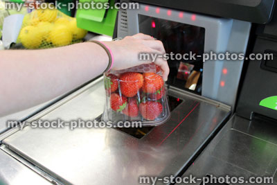 Stock image of girl scanning shopping (strawberries) at self service supermarket checkout till (self checkout)