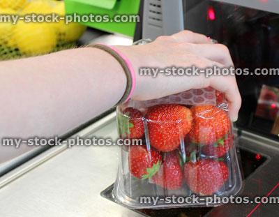 Stock image of supermarket self checkout machine, customer scanning strawberries using barcode