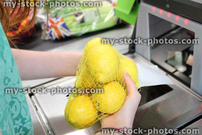 Stock image of girl scanning shopping (lemons) at self service supermarket checkout till (self checkout)