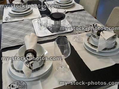 Stock image of black and white themed dinner table setting, crockery / plates, napkins