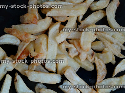Stock image of greasy chips, unhealthy takeaway fast food, black oven tray