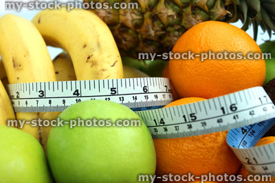 Stock image of tape measure with bananas, apples, oranges, pineapple, fruit
