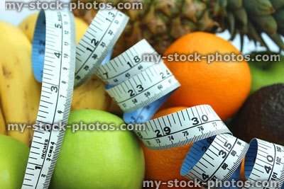 Stock image of tape measure with bananas, apples, oranges, pineapple, avocado