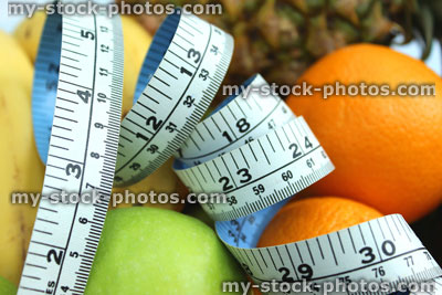 Stock image of tape measure with bananas, apples, oranges, pineapple, fruit