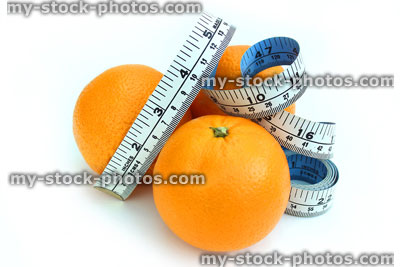 Stock image of tape measure with oranges, three fresh organic oranges