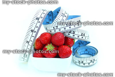 Stock image of tape measure with fresh organic strawberries in dish