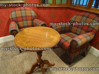 Stock image of tartan fabric armchairs, antique round wooden coffee table
