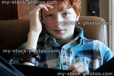 Stock image of teenage boy relaxing on sofa with tablet computer
