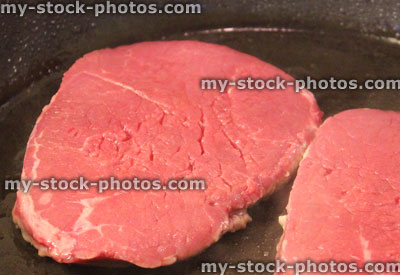 Stock image of raw tenderloin steaks in frying pan, organic beef
