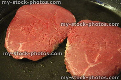 Stock image of raw tenderloin steaks in frying pan, organic beef