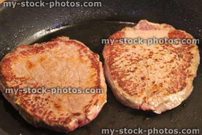 Stock image of medium rare tenderloin steaks in frying pan, organic beef