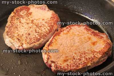 Stock image of medium rare tenderloin steaks in frying pan, organic beef