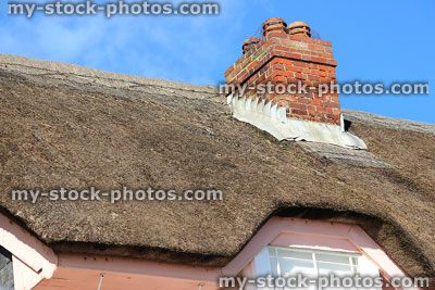 Stock image of pink thatched cottage roof with brick chimney pot