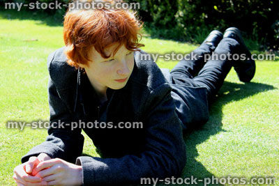 Stock image of red haired boy lying stretched out on a manicured lawn