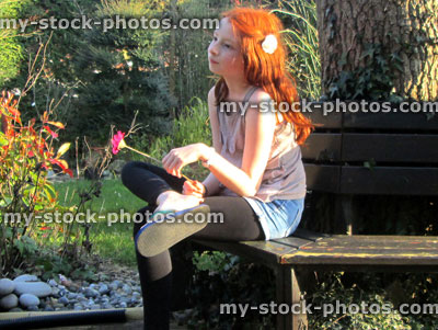 Stock image of pensive young girl sitting in garden sunlight, thinking to herself