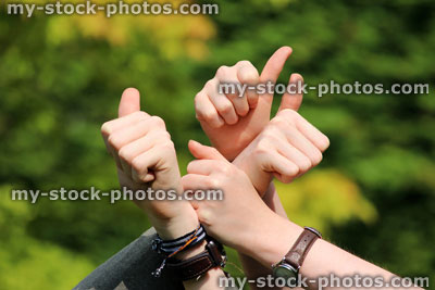 Stock image of thumbs up, four hands in garden, multiple thumbs, four