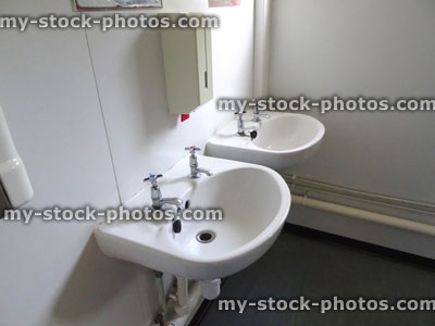 Stock image of two dirty white ceramic sinks in public toilet