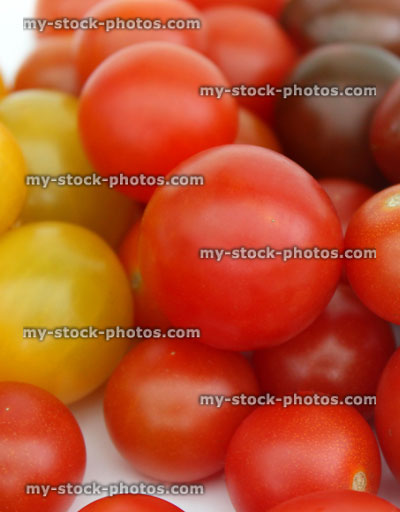 Stock image of yellow, green / purple and red cherry tomato piles