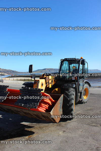Stock image of tractor next to beach promenade and harbour walls