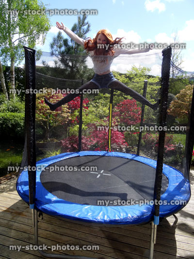 Stock image of girl jumping on trampoline in garden, safety net