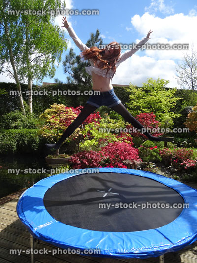 Stock image of girl doing star jump, bouncing high above trampoline