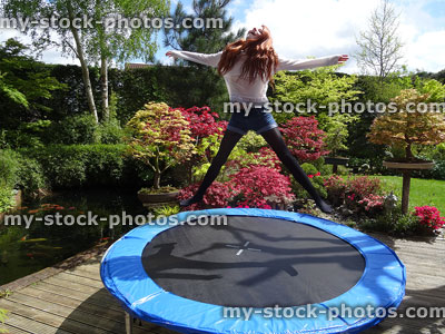 Stock image of girl bouncing on garden trampoline without safety net