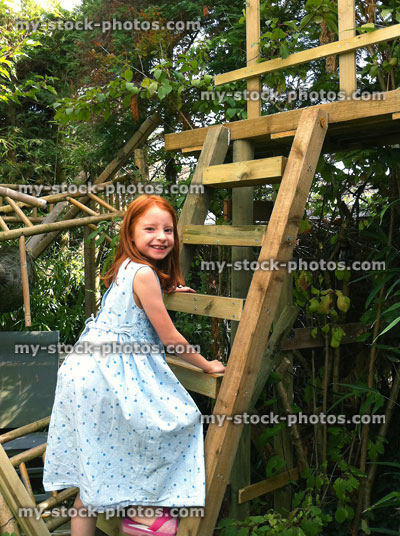 Stock image of girl climbing ladder to wooden tree top walkway