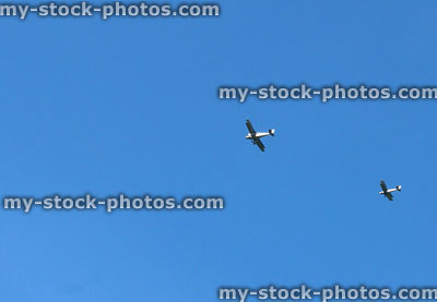 Stock image of two biplane aircraft flying overhead in blue sky