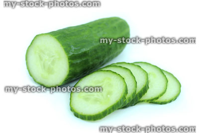 Stock image of fresh organic cucumber cut in half, with slices of cucumber