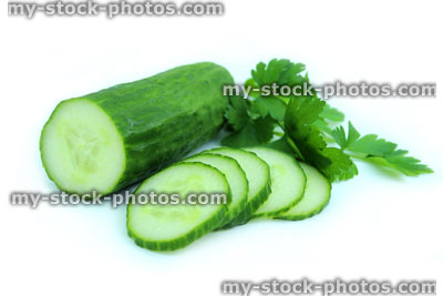 Stock image of fresh organic cucumber cut in half, with slices and parsley