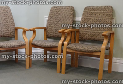 Stock image of wooden chairs with brown cushions, hospital / doctor's waiting room