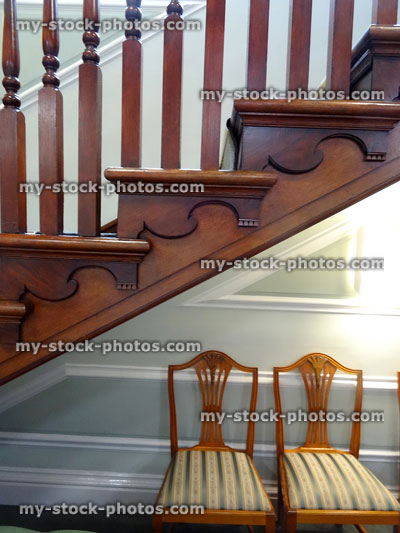 Stock image of wooden stair bannisters / spindles, staircase, antique chairs striped cushions