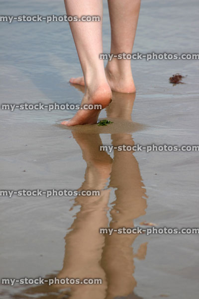 Stock image of girl walking on wet beach, reflections in the sand / sea