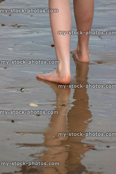 Stock image of girl walking on wet beach, reflections in the sand / sea