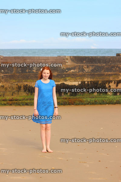 Stock image of girl walking barefoot on beach / seaside sand, wooden sea groyne