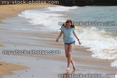 Stock image of girl walking barefoot on beach, sea waves, paddling in sea