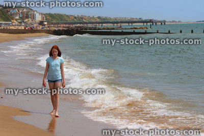 Stock image of girl walking barefoot on beach, sea waves, paddling in sea