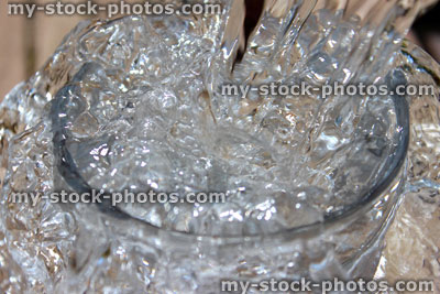 Stock image of water being poured into glass, splashing and sparkling