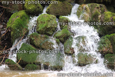 Stock image of waterfall with moss-covered rocks, water cascading into river