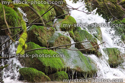Stock image of natural waterfall cascade of water, over mossy-rocks, into-stream