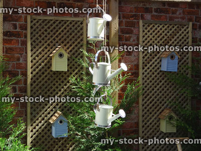 Stock image of hanging watering cans mobile, garden trellis, nesting boxes