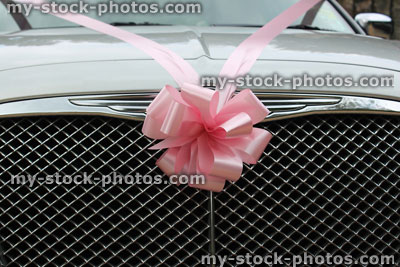 Stock image of silver chauffeured limousine decorated with pink ribbon, wedding car bow