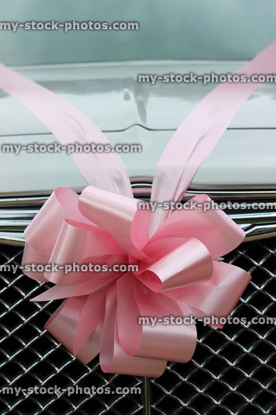 Stock image of silver chauffeured limousine decorated with pink ribbon, wedding car bow